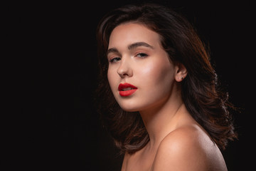 Fototapeta premium Beautiful woman with bright makeup posing isolated over black background. Image of young beautiful woman with red lips