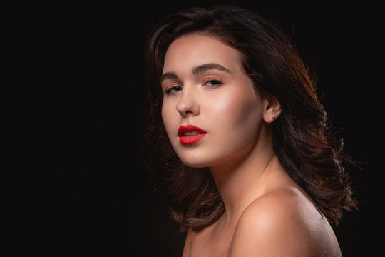 Beautiful woman with bright makeup posing isolated over black background. Image of young beautiful woman with red lips