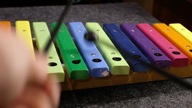 Child playing with a colorful xylophone and learning music. Child development, learning to play a musical instrument. Zooming out movement