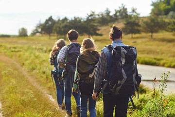 A group of tourists with backpacks is walking in nature