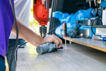 close up technician catch and drilling key or switch engine start of sedan car by electric drill for repair on table