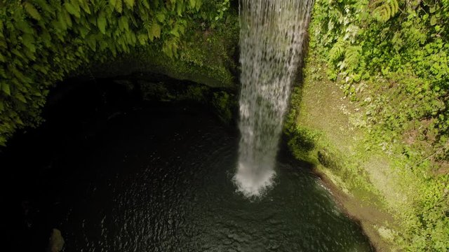 Aerial drone flight up from the cave of Air Terjun Tibumana waterfall, Bali, Indonesia, 4k