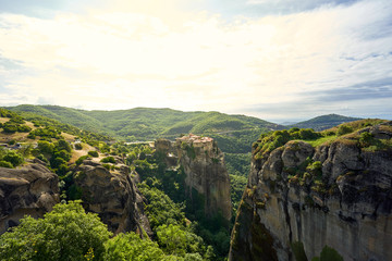 Amazing Meteora Monastery in Greece. Fantastic view at mountains and green forest against epic blue sky with clouds. UNESCO