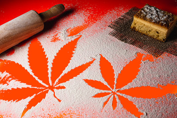 cooking cannabis food. Trail of cannabis leaf on white flour on Lush Lava color table. battledore....