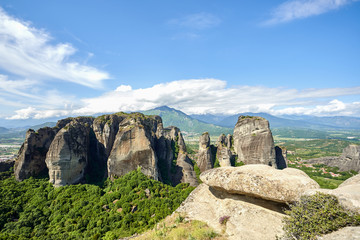 Amazing Meteora Monastery in Greece. Fantastic view at mountains and green forest against epic blue sky with clouds. UNESCO