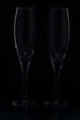 Close up view of  contour of a beautiful two  slim, tall and elegant champagne glasses isolated on a black background. Beautiful background.