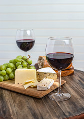 Two glasses of red wine and tasty snacks on dark wood table with white background