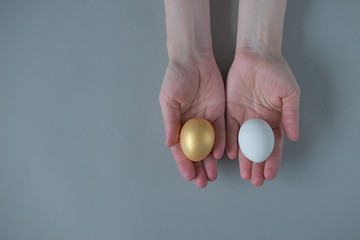 Hands holding white and gold eggs, top view. Nobody. Choice. Alternative.Wealth and poverty.