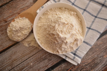 farina bianca di grano in ciotola su tavolo di legno e cucchiaio di legno da cucina ingrdiente per cucinare