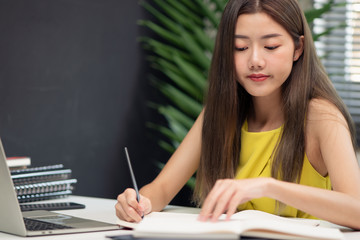 Young beautiful Asian office woman is busy working with stocking, paperwork, accounting while checking with mobile phone at the desk in the office, concept office lifestyle, effective working woman.