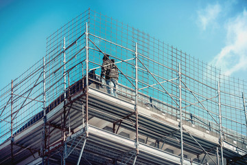 metallic safety net in construction industry, man working on scaffolding (unidentified person)