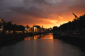 Dublin's cityscape during a colorful sunset with clouds and seagulls over Liffey river