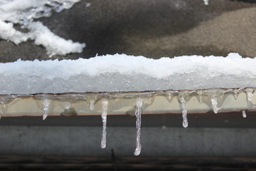Snow icicles on roof in spring time