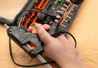 hand repairs glue gun using tool