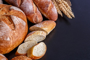 Bakery - gold rustic crusty loaves of bread and buns on black chalkboard background.