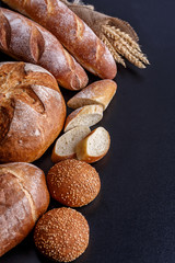 Bakery - gold rustic crusty loaves of bread and buns on black chalkboard background.