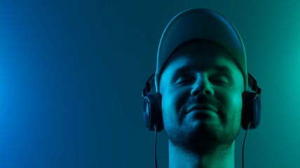 Satisfied young man listening to music on headphones. His eyes are closed. Copy space
