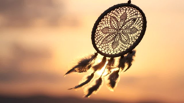 Dream catcher with white feathers flying in wind sun. Hunter of dreams against sunset. Summer time, textures, shaman, background, nature, craft, feathers. dreams, happiness 4 K slow-motion