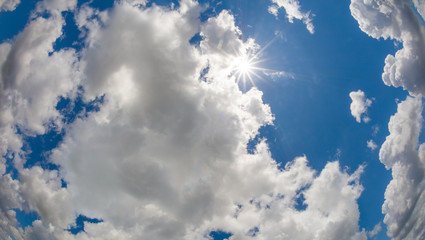 Sunburst in blue sky and big white clouds