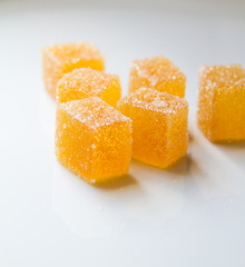 Orange pate de fruit (jelly, marmalade, fruit candy) covered with sugar on a white background, back view
