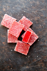 Strawberry pate de fruit (jelly, marmalade, fruit candy) covered with sugar on a dark background,...