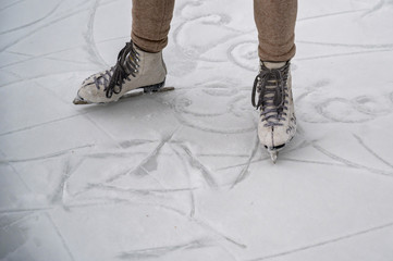 Figure skating on the street at an outdoor ice rink. Close-up of the skater's legs on ice. A woman goes in for sports.