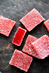 Strawberry pate de fruit (jelly, marmalade, fruit candy) covered with sugar on a dark background,...