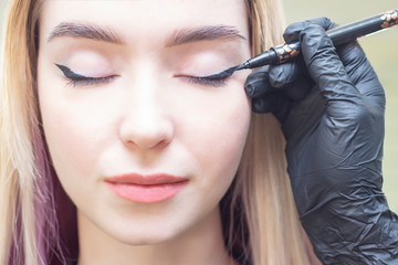 Obraz premium Make-up artist puts makeup on the girls eyes. eyeliner. make eyeliner eyeliner. Beauty saloon