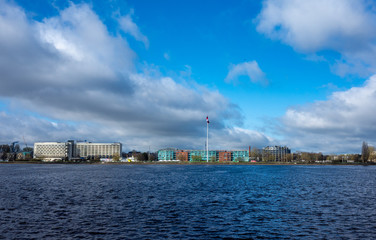 Naklejka premium April 26, 2018 Riga, Latvia. Flagpole with the giant flag of Latvia on the banks of the Daugava.