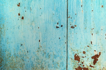 Old iron sheet with peeling blue paint and rusty spots.