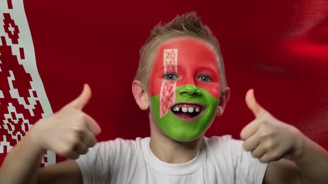 Joyful fan on the background of the flag of Belarus. Happy boy with painted face in national colors. The young fan rejoices in the victory of his beloved team. Success. Victory. Triumph.