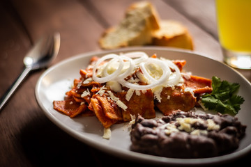 Plato de Chilaquiles y frijoles caseros con crema y queso cotija cafe y jugo desayuno tradicional mexicano