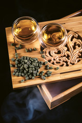 Chinese tea ceremony. Cups at tea board with hot green tea, milky oolong ginseng on black background