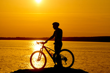 Fototapeta na wymiar Silhouette of a bike on sky background on sunset on a mountain top.