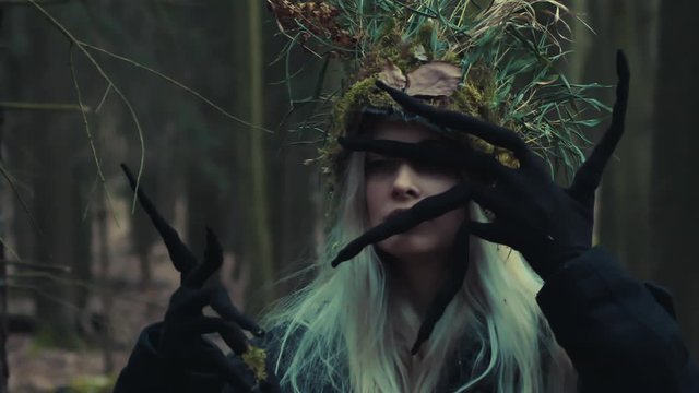 Forest witch showing long black fingers and dramatic face, occultism symbolism