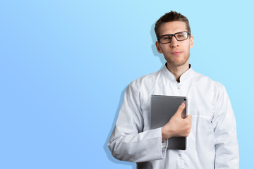 Naklejka na ściany i meble young male doctor holding a digital tablet isolated standing near the color wall with copy space