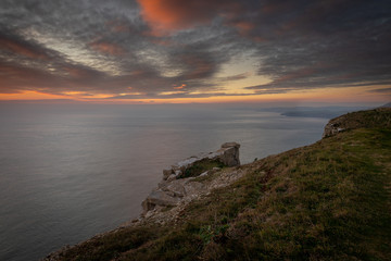 Naklejka premium Beautiful vibrant sunset over sea and clifftop