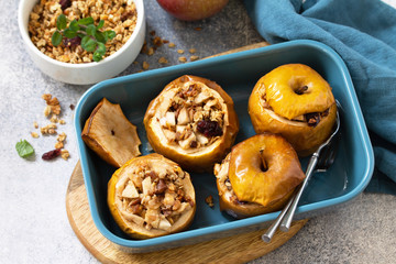 Diet menu. Healthy dessert. Baked apples with walnuts, honey and granola on slate, stone or concrete background.