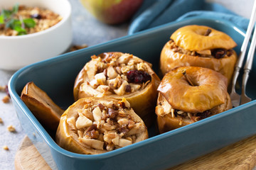 Diet menu. Healthy dessert. Baked apples with walnuts, honey and granola on slate, stone or concrete background.