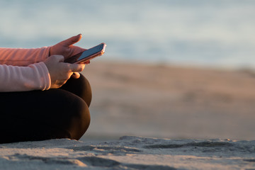 Woman hands with cellphone on the beach.