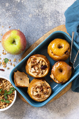 Diet menu. Healthy dessert. Baked apples with walnuts, honey and granola on slate, stone or concrete background. Top view flat lay background. Copy space.