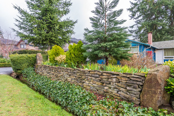 Fragment of a house with stone wall and outdoor landscape.