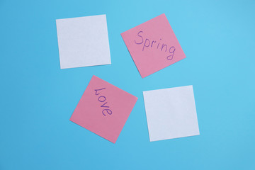 papers with the inscriptions love, spring on a blue background. copy space