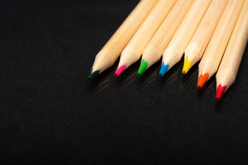 Multi-colored wooden pencils. Dark black background. Natural materials. Stationery. Office tools....