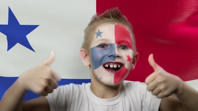 Joyful fan on the background of the flag of Panama. Happy boy with painted face in national colors. The young fan rejoices in the victory of his beloved team. Success. Victory. Triumph.
