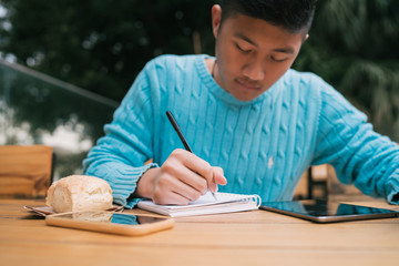 Asian man studying in coffee shop.