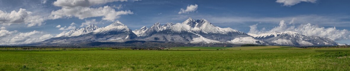 Extra wide panorama of High Tatra main ridge of mountains during April with snowy hills and blue sky with clouds, Vysoke Tatry, Slovakia - Powered by Adobe