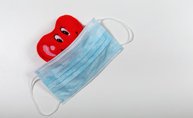 A medical mask is dressed on a toy heart
