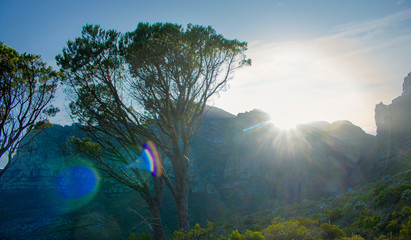 Sunlight popping over mountains at sunrise in nature in Camps Bay.