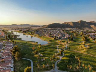 Aerial view of golf course surrounded by town houses and luxury villas during sunset time....
